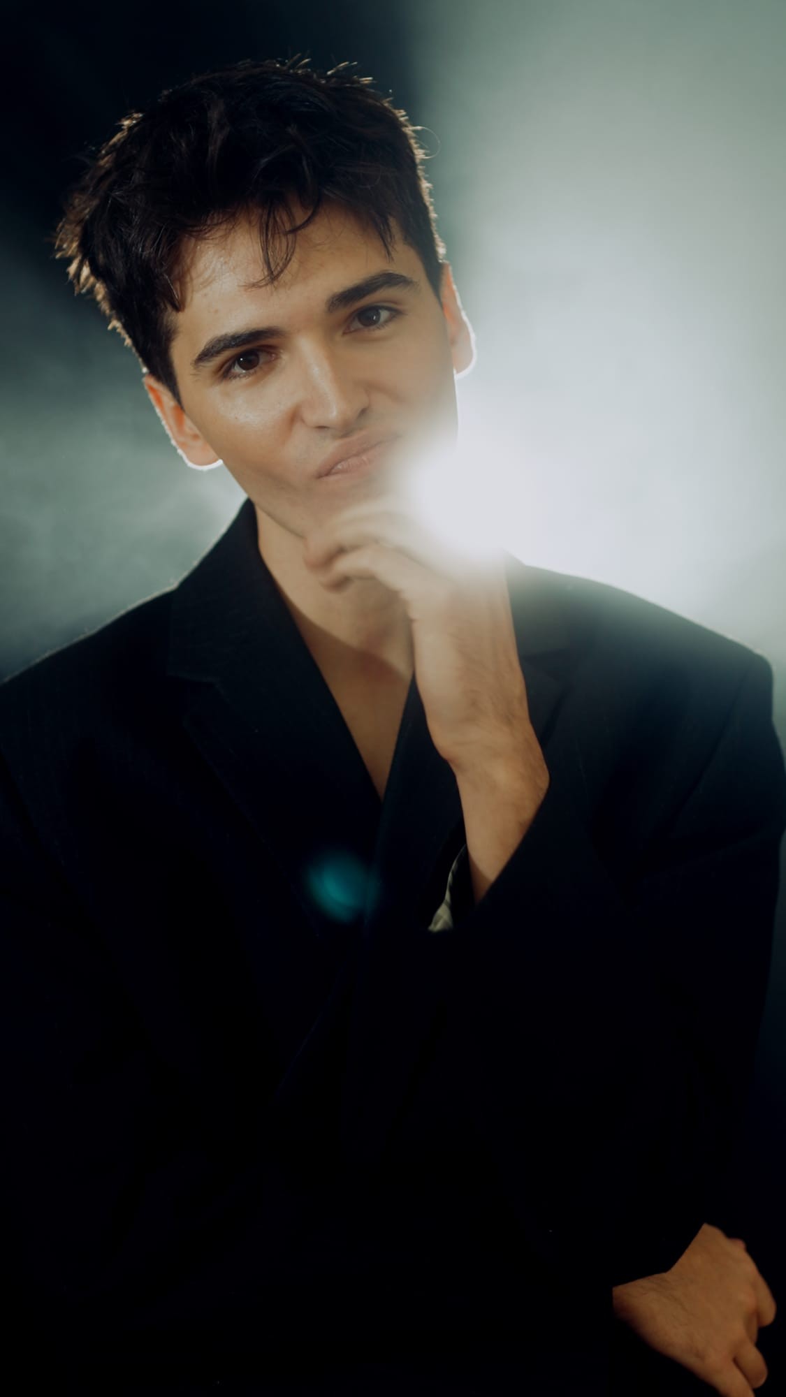 Portret aktora w czerni, dłoń przy kołnierzu